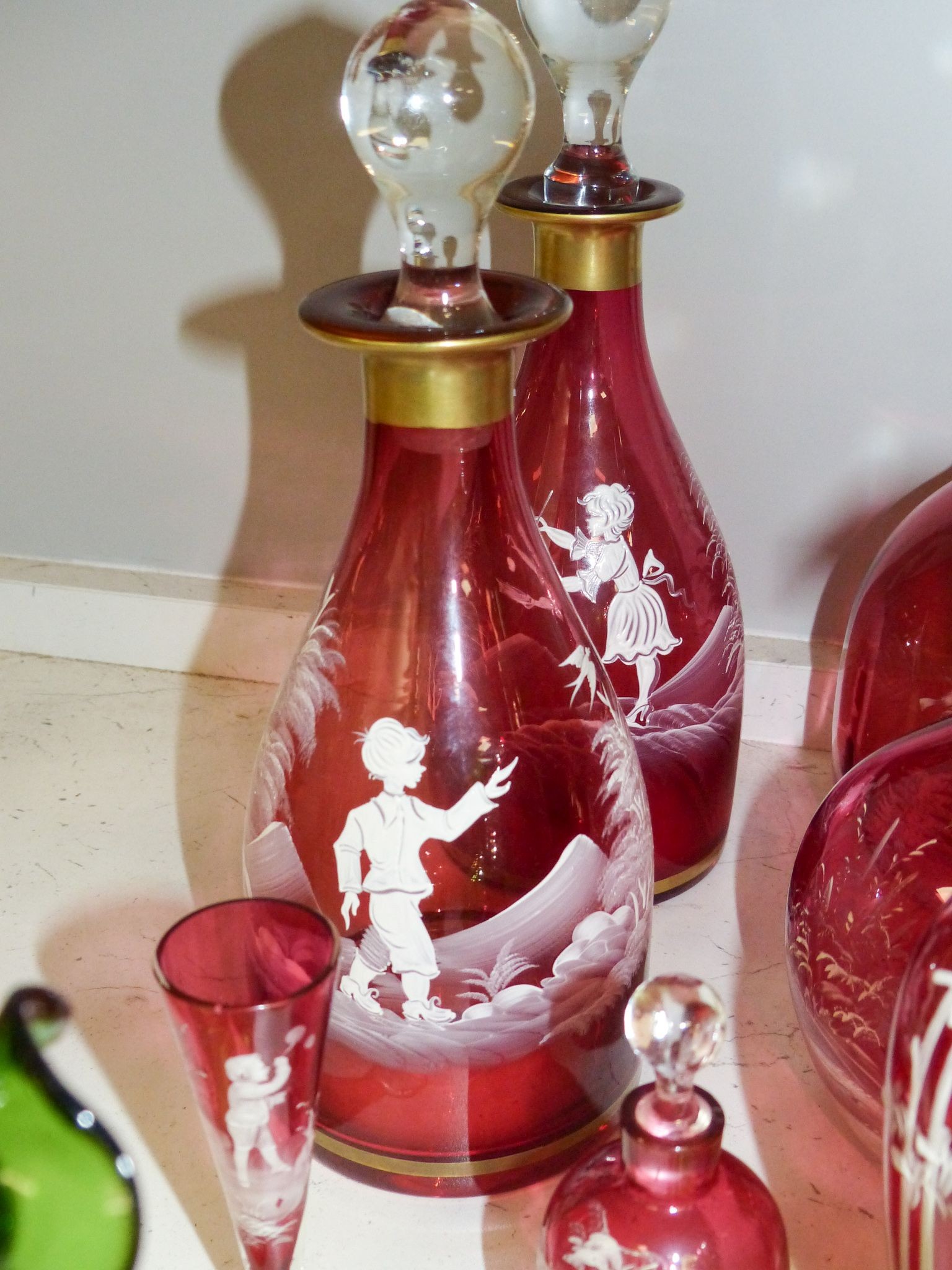 A collection of Mary Gregory cranberry and green glass decanters, jug etc (9), tallest 28.5 cm